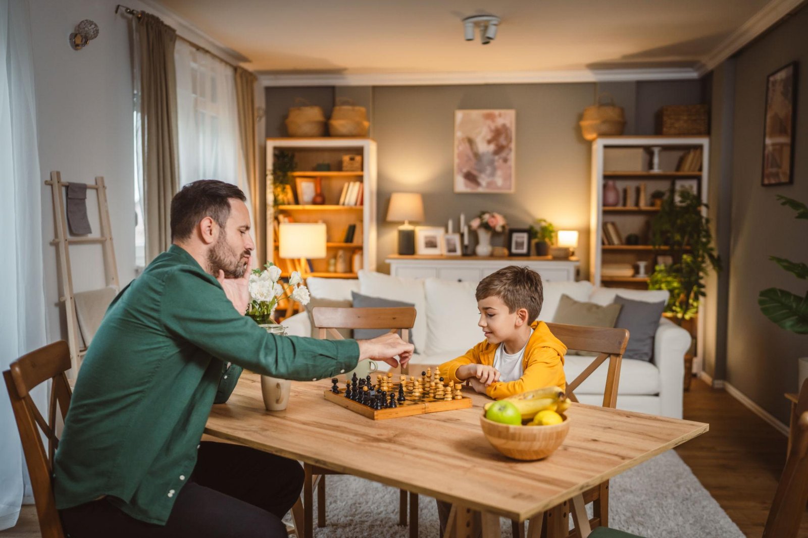 Parent and child enjoying a screen-free evening playing chess together at home.