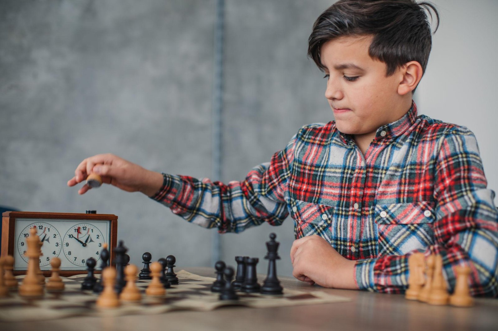 Young tournament player practicing time management by hitting the chess clock after a move